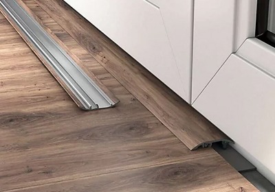 Aluminium door threshold strip fitted between laminate flooring in a modern UK home doorway