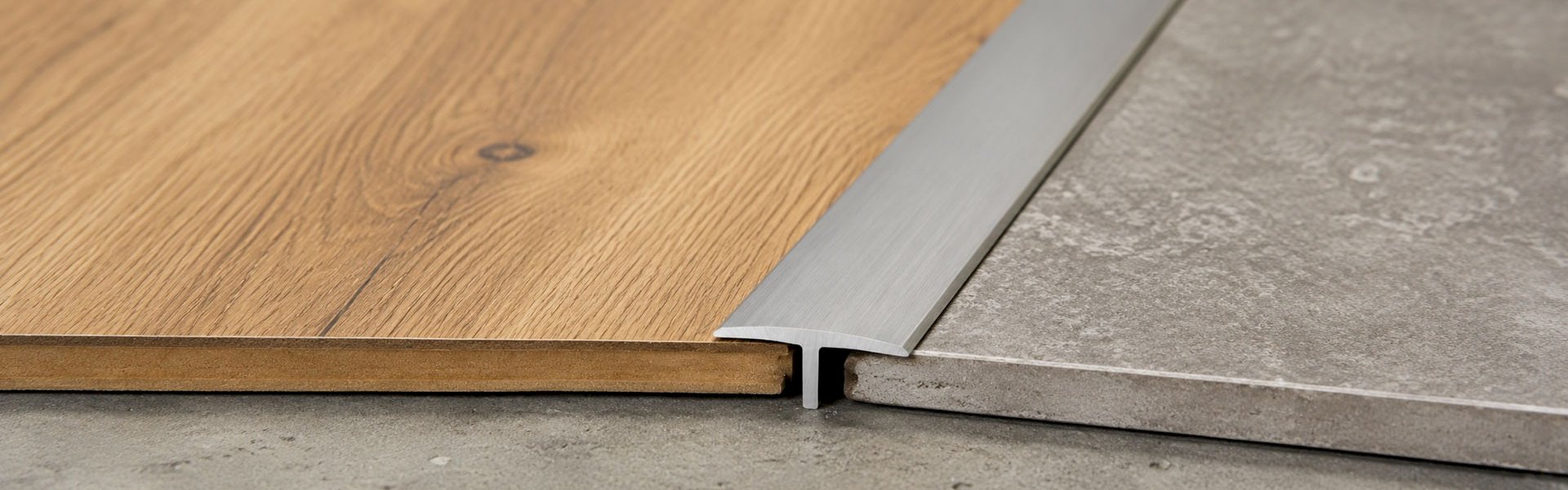 Metal T-spline profile between wood and tile flooring.